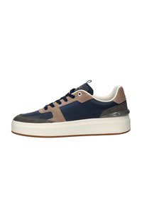 Sneaker met een marineblauwe textielen bovenkant, lichtbruine en grijze suede accenten, een dikke witte zool en ronde veters. Metalen oogjes zichtbaar.