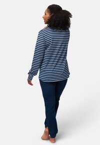 Top a maniche lunghe a righe blu navy e bianche abbinato a pantaloni blu navy uniti. Materiale in cotone morbido, vestibilità comoda, polsini a coste e orli alla caviglia.