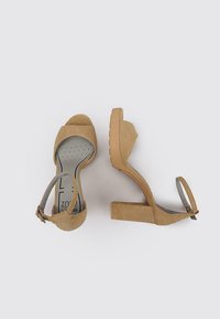 Sandalias de tacón alto de gamuza marrón claro con tira en el tobillo, punta abierta redondeada, tacón de cuña texturizado y plantilla acolchada con un patrón de puntos.