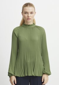 Blusa verde plissettata con maniche lunghe, colletto arricciato alto e tessuto testurizzato, con leggeri arricciamenti all'orlo per una silhouette morbida.