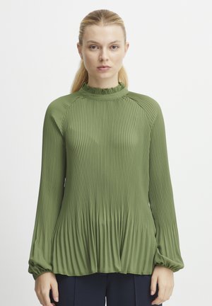 Blouse plissée verte à manches longues, avec un col haut à volants et un tissu texturé, présentant de douces fronces à l'ourlet pour une silhouette fluide.