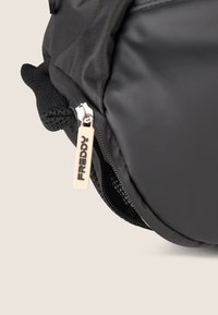 Zaino nero in tessuto testurizzato, con cerniera argentata e un tirante beige etichettato "FREDDY". Include una tasca laterale in rete.