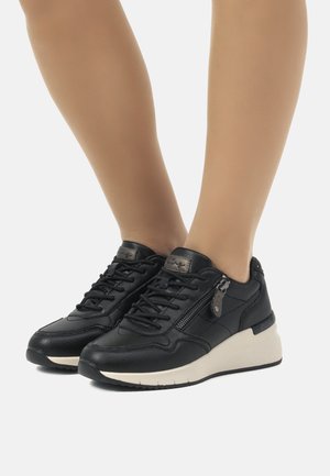 Zapatillas negras de cuero con acentos texturizados, suelas blancas contrastantes y diseño con cordones. Cuenta con una cremallera decorativa en el costado.