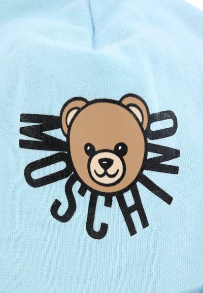 Cappello a maglia azzurro chiaro con grafica di un orso marrone e testo nero, che mostra un design giocoso e una texture liscia.