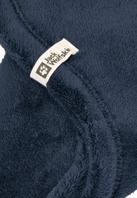 Coperta in pile blu navy con una superficie morbida e testurizzata e un'etichetta cucita con il logo "Jack Wolfskin" in bianco su uno sfondo crema.