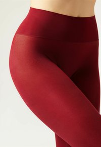 Burgunderfarbene Leggings aus dehnbarem Stoff mit einem hohen Bund, die eine glatte Textur und eine enge Passform um Hüften und Oberschenkel bieten.
