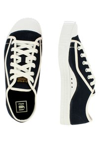 Zapatillas de lona azul marino con punta y suela de goma blanca. Presentan cordones blancos, detalles laterales y una marca en la lengüeta. Perfil plano.