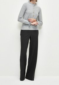 Haut gris à manches longues rayé avec un col ondulé et un rabat de boutons, associé à un pantalon noir taille haute à jambes droITES.