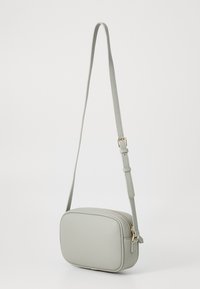 Ανοιχτό γκρι δερμάτινη τσάντα χιαστί με ορθογώνιο σχήμα, χρυσό φερμουάρ, ρυθμιζόμενο λουρί και υφή.