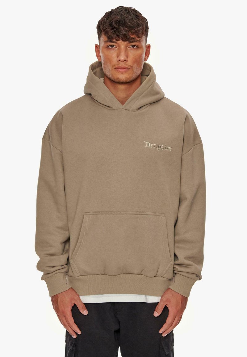 Beige Kapuzenpullover aus weichem Stoff, mit einer Kängurutasche, Kordelzug-Kapuze und dezentem Logo in der oberen linken Ecke.