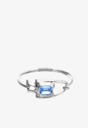 Bracelet en argent conçu comme une épingle de sûreté avec une grande pierre précieuse rectangulaire bleue sertie au centre.