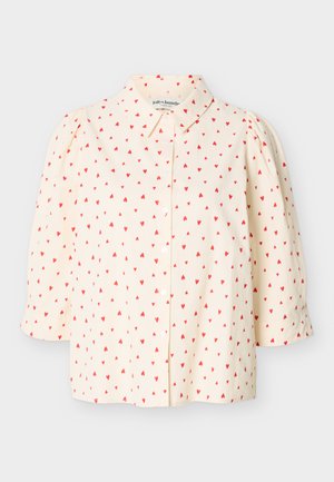 Blouse crème à motif de petits cœurs rouges, boutonnage sur le devant, manches ballon trois-quarts et col classique.