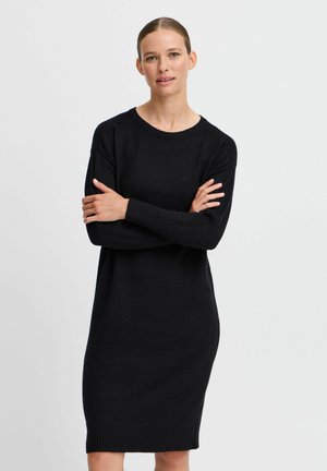 Black knit dress with long sleeves, a rounded neckline, ribbed texture at cuffs and hem, and a relaxed fit reaching mid-thigh.