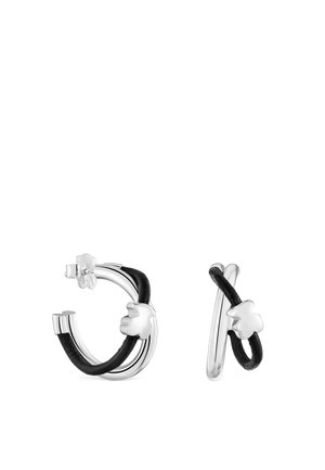 Pendientes de aro de plata con cordones de cuero negro retorcidos alrededor, cada uno con un pequeño colgante floral de plata sobre un fondo blanco.