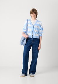 Light blue striped cardigan with a v-neck and buttons, paired with high-waisted blue jeans and light blue shoulder bag. Silver sneakers.