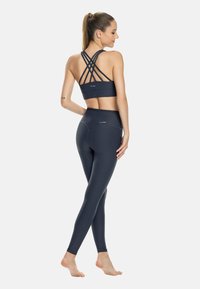 Navy urheiluleggingsit ja niille sopiva ristiin selän urheiluliivi, joka on valmistettu sileästä, kevyestä kankaasta. Ominaisuuksiin kuuluu korkea vyötarina ja ristikkäiselä selkätieto.
