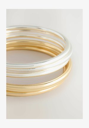 Sada troch hladkých kovových náramkov, s alternujúcou striebornou a zlatou farbou. Kružnicový tvar so vylešteným povrchom a reflexnou plochou.