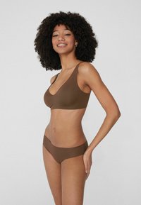 Brązowy stanik bezszwowy z dekoltem w serek i szerokimi ramiączkami, w zestawie z dopasowanymi, niskimi majtkami. Gładka faktura, minimalistyczny styl.