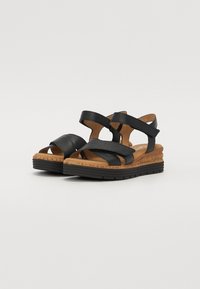 Mustad mustad, millel on laiad ristitatud rihmad, kork vaheplaat ja tekstureeritud kummist välistald haardeks ja mugavuseks.