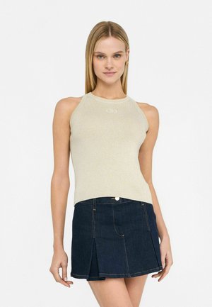 Haut sans manches en or clair avec une texture côtelée et un col montant, associé à une mini-jupe en denim foncé avec un bouton devant et des plis.