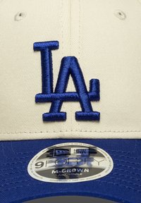 Καπέλο μπέιζμπολ με μπεζ μπροστινό μέρος και μπλε γείσο. Διαθέτει το ξεχωριστό μπλε κεντητό λογότυπο "LA". Περιλαμβάνει κυκλικό ετικέτα στο γείσο.