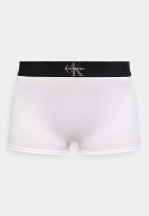 Valgete meeste bokserpüksid musta elastse vöökohaga, millel on halli ja valge Calvin Kleini logo.