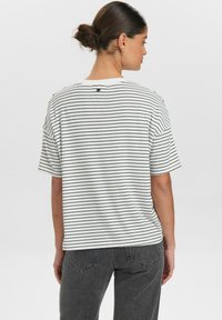 Randig t-shirt i vitt och marinblått, med avslappnad passform, korta ärmar och rund halsringning, tillverkad av mjukt bomullsmaterial.