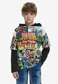 Lyhythihainen, monivärinen huppari, jossa on Marvel-superhero-aiheisia grafiikoita, musta pitkähihainen aluskerros ja farkut, joissa on painettu yksityiskohta.