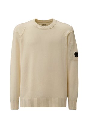 Maglione lavorato a maglia color crema con collo rotondo, orlo e polsini a coste, presenta una tasca applicata sul manica sinistra con un accento di bottone nero.