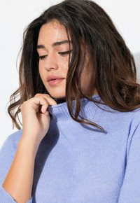 Maglione a collo alto azzurro chiaro realizzato in materiale morbido, con collo e polsini a coste, dal fit rilassato e dalla texture liscia.