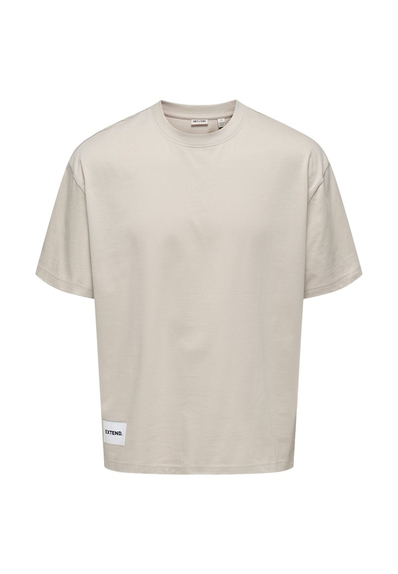 T-shirt corto di colore beige chiaro realizzato in tessuto morbido. Presenta un collo tondo e un'etichetta cucita all'orlo con la scritta "EXTEND."