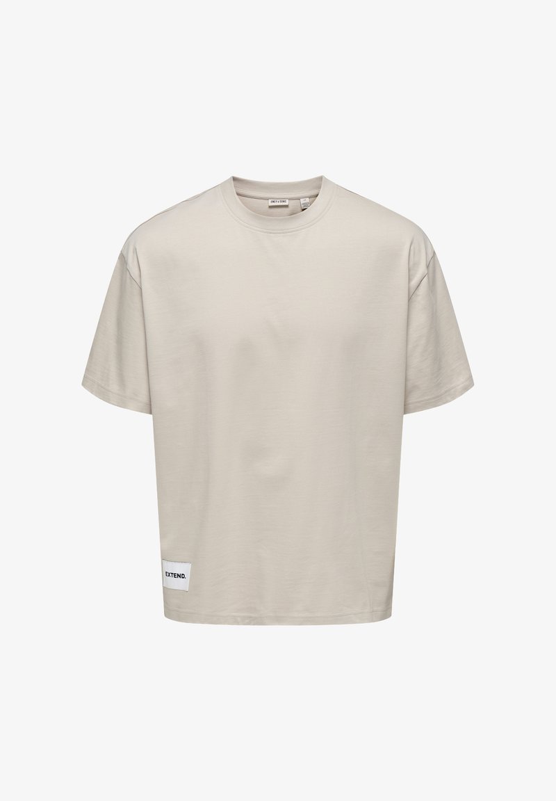 T-shirt corto di colore beige chiaro realizzato in tessuto morbido. Presenta un collo tondo e un'etichetta cucita all'orlo con la scritta "EXTEND."