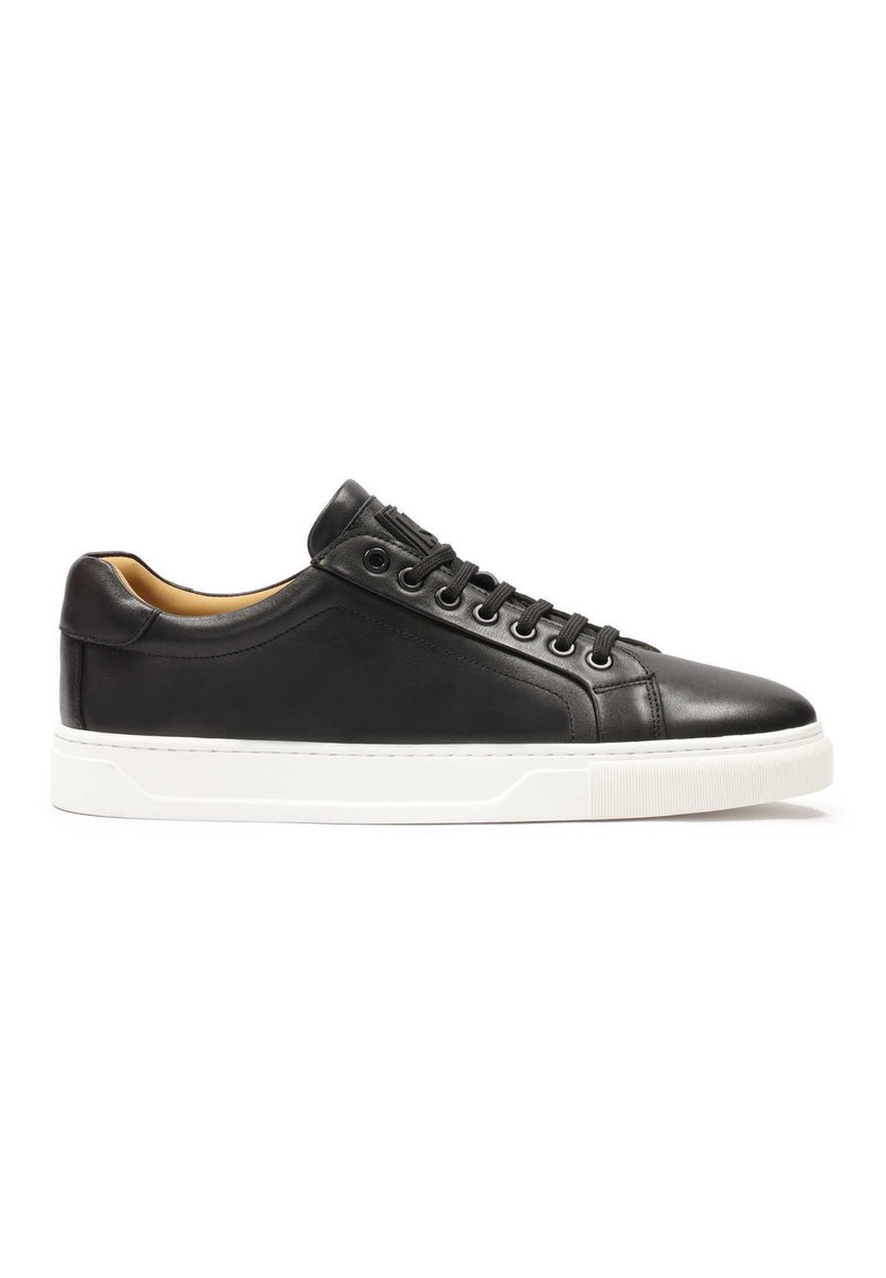 Zapatillas de cuero negro con una textura suave, que presentan suelas de goma blanca, cordones redondos y un sutil branding en relieve en la lengüeta.