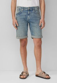 Shorts en jean de couleur bleu clair, avec des poignets roulés et cinq poches. Associés à des sandales à glissière marron avec des doubles boucles et un lit de pied doux.