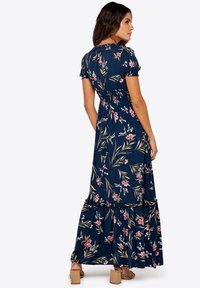 Marinblå blommig maxiklänning med korta puffärmar, figurnära bodice och volangnederdel. Har rosa och vita blommönster.