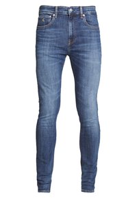 Slim-fit jeans i mörkblå denim. Funktioner inkluderar framfickor, metallbeslag och subtila sömdetaljer. Mjuk, texturerad tyg.