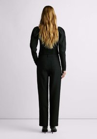 Zwarte textuur-fitting top met pofmouwen, gecombineerd met hoge taille rechte broek, afgemaakt met zwarte hoge hakken.