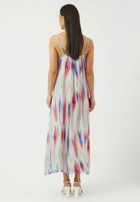 Maxiklänning med ett flödande mönster, med färgglada abstrakta mönster i nyanser av blått, rött och vitt. Tunna axelremmar och en slät textur.