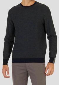 Pull marin avec un ribbing texturé, col rond et manches longues. Présente des poignets noirs contrastants avec un petit accent.