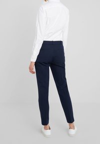 Housut navy-sävyssä, räätälöity juuri sinulle, valmistettu kudotusta kankaasta. Niissä on slim fit -malli, takataskut ja sileä pinta, yhdistettynä valkoiseen paitaan.