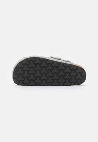 Gray felt slip-on shoe with a textured black rubber sole and Velcro straps. Rounded shape, minimal design, suitable for casual wear.