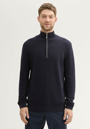 Marinefarbener Pullover mit Viertelreißverschluss, strukturiertem Strick, gerippten Bündchen und Saum sowie Stehkragen. Lockerer Schnitt, ideal zum Schichten.