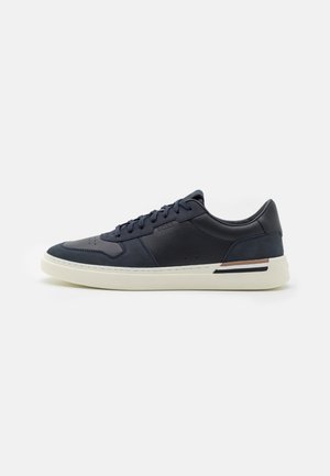 Marineblauer Low-Top-Sneaker mit weißer Sohle, Schnürung vorne und dezentem Markenlogo an der Seite, im Profil auf einfarbigem Hintergrund gezeigt.