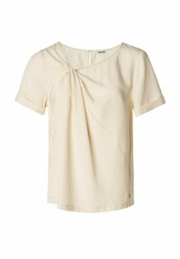 Blouse courte à manches courtes beige clair avec un détail de nœud torsadé sur l'épaule gauche et un col rond.