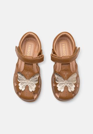 Brune børnesandaler med gyldent sommerfugle-dekoration foran og justerbare velcro-remme, mærket "FRIBOO" indeni.