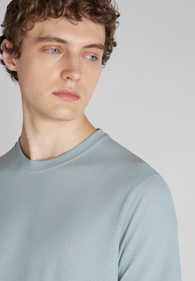 Helles blaues Rundhals-Sweatshirt aus weichem Material, mit glatter Textur und normaler Passform. Sichtbare Nähte am Kragen und an den Schultern.
