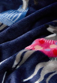 Gros plan sur un tissu bleu marine doux avec des dessins imprimés de chiens gris portant des pulls colorés en bleu et rose.