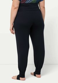 Pantalones jogger negros y elásticos con una cintura ancha y puños ajustados en los tobillos. Textura suave, diseñados para la comodidad y facilidad de movimiento.