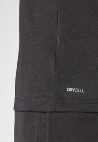 Zwart sportshirt met een gladde textuur. Voorzien van het witte "DRYCELL" logo nabij de zoom. Eenvoudig ontwerp met een ronde halslijn.