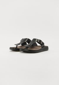 Mustad musta flip-flop sandaalid, millel on tekstureeritud jalanõude sisetald, reguleeritav rihm metallist klambriga ja vormitud tald mugavuse ja stabiilsuse tagamiseks.